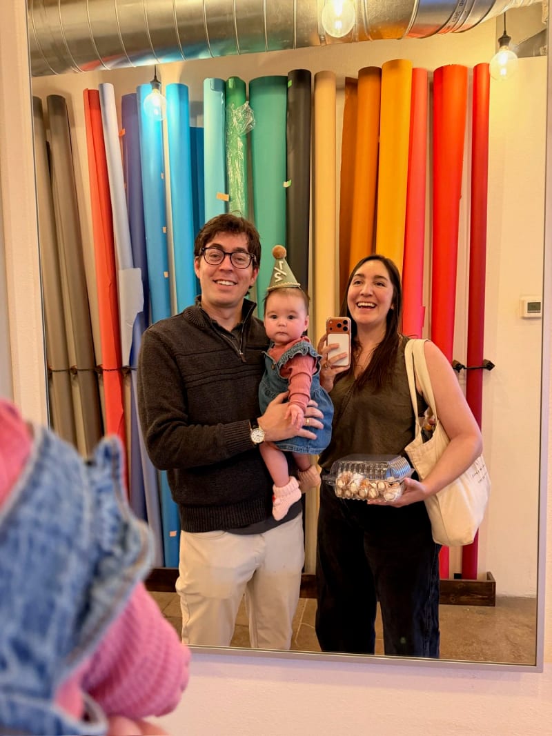 Nicole Riley with her husband and daughter Jodie, photographed in a mirror in front of a wall of coloured paper backdrops