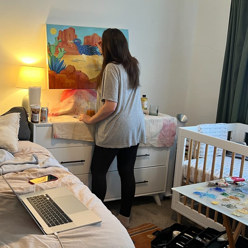 Nicole painting a desert roadrunner scene in her bedroom studio
