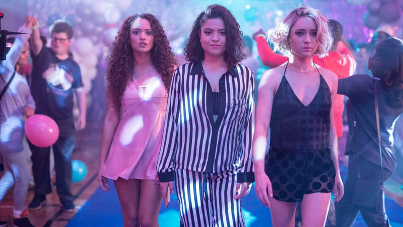 Three friends walking through a school dance in party outfits