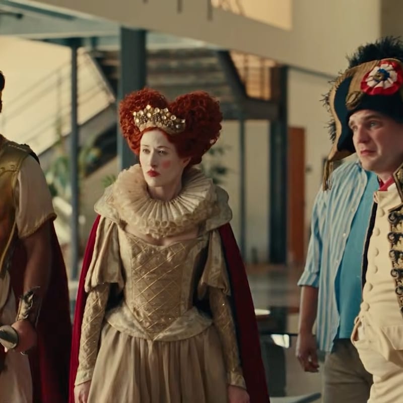 A red-headed queen in period costume walking with two other costumed characters
