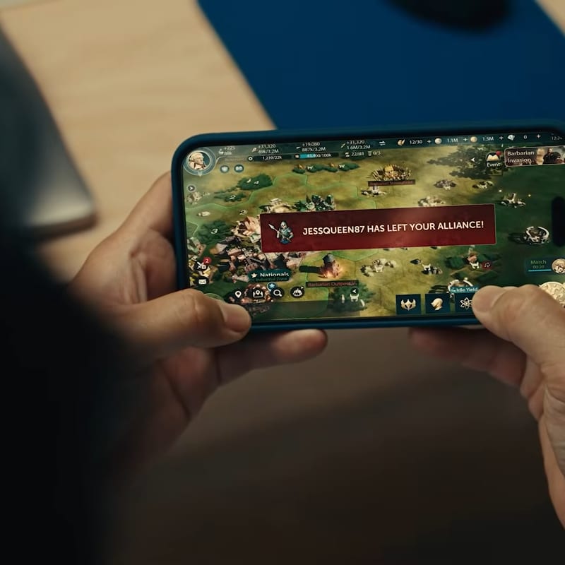 Hands holding a phone showing the Civilization mobile game interface