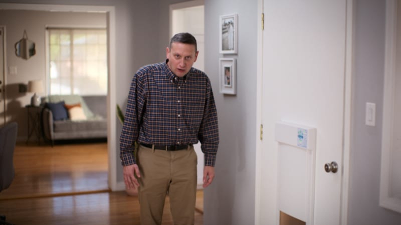 A man standing in a hallway beside a dog door