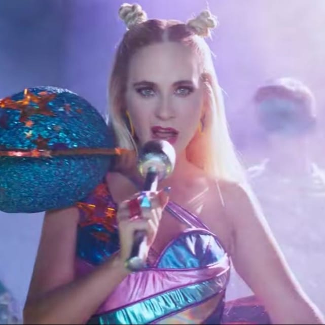 Katy Perry singing into a microphone in a sparkly space-themed costume