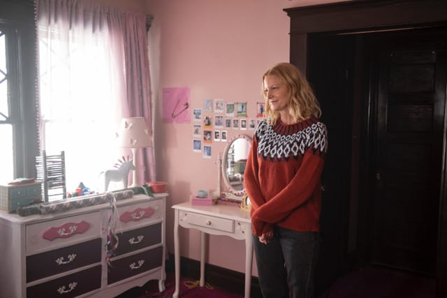 A woman smiling in a pink childhood bedroom