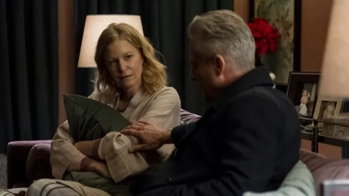 A woman on a couch holding a pillow while a man sits beside her