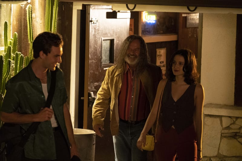 Three characters walking out of a desert bar at night