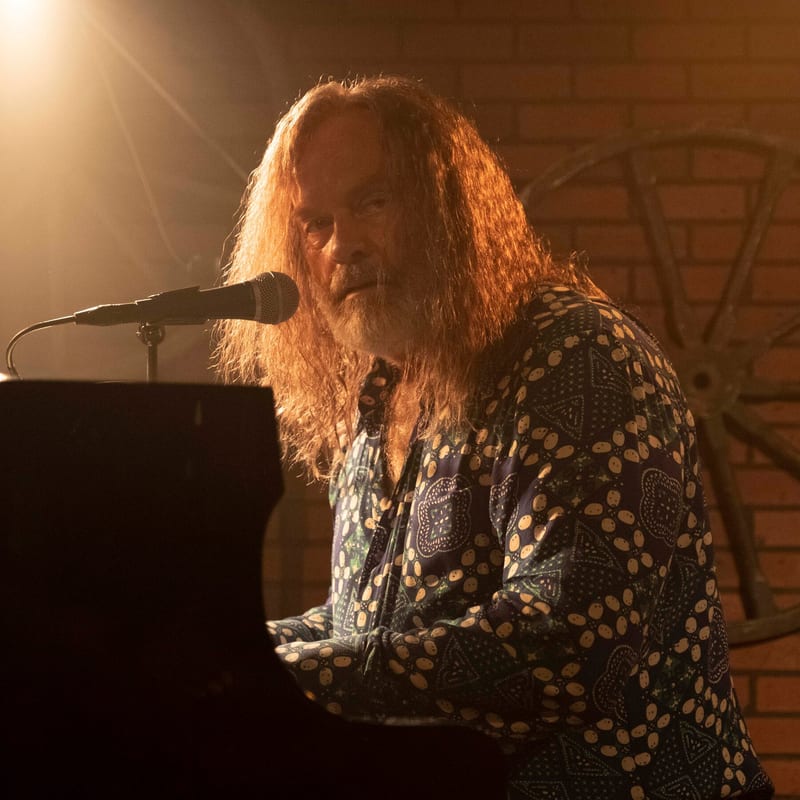 A musician singing at the piano under warm stage light