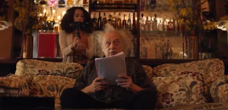 An older man reading a script on a floral couch