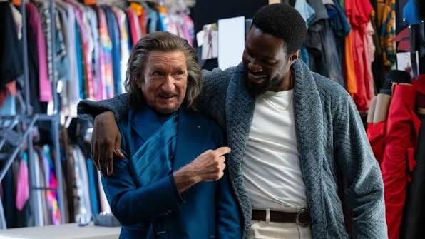 Two men laughing beside a wardrobe clothing rack