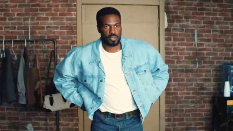 Man in a denim jacket standing in a brick-walled room